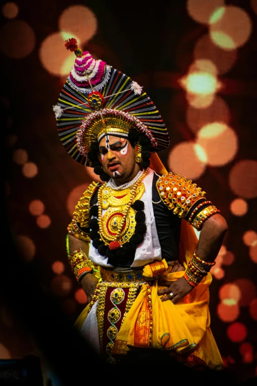 man with elaborate costume posing with headpieces on stage