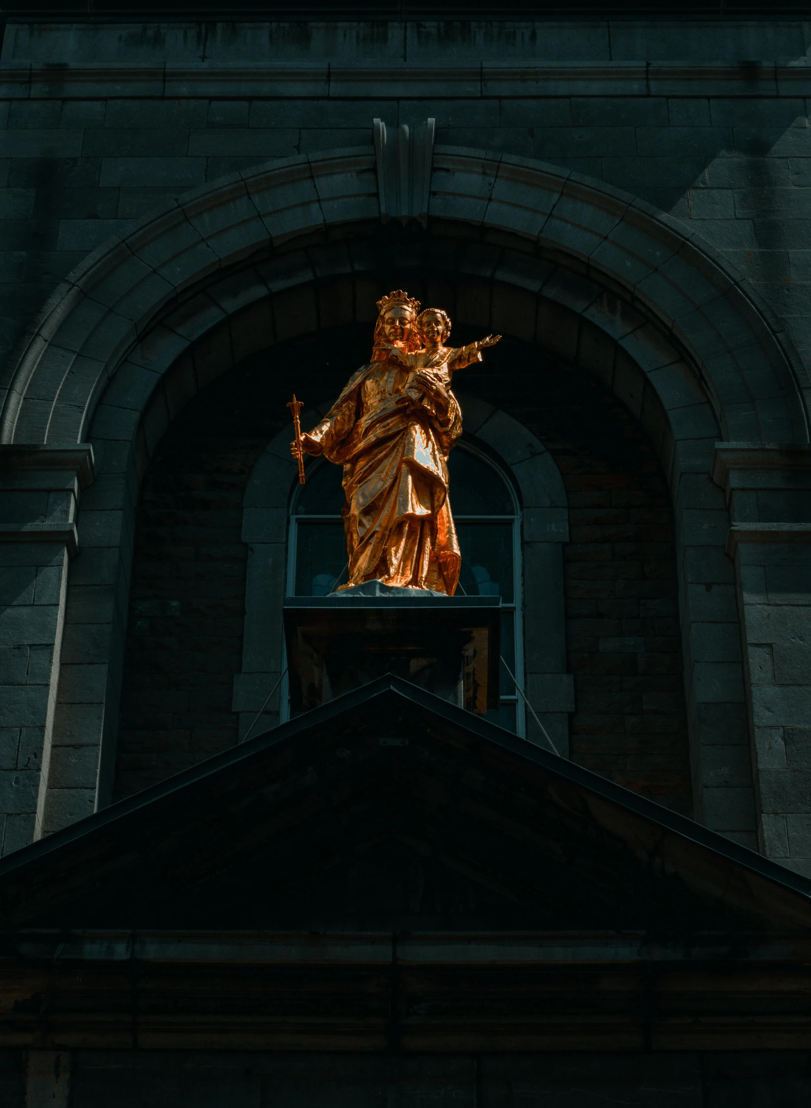 a golden statue is standing in an arch