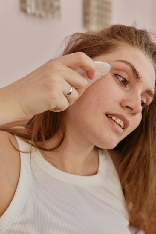 a woman putting soing under her eye with a toothbrush