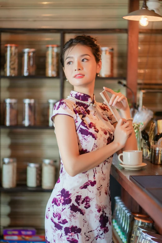 a woman standing at a counter holding a glass with wine in it