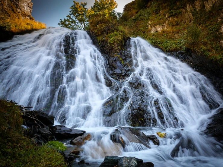 a waterfall in a forest near a mountain side