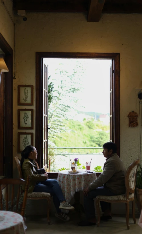 man and woman sitting at the table in front of the open door