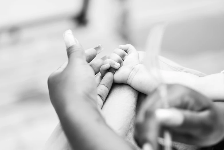 a close up of a small baby's hand and mother's hand