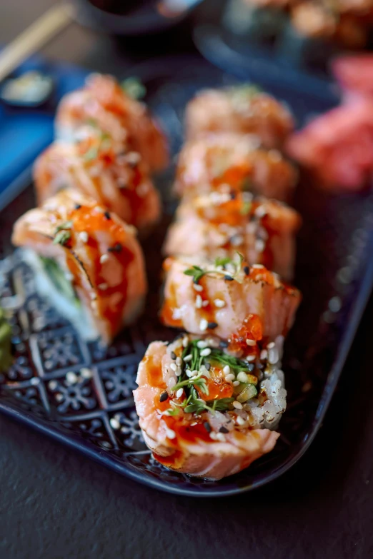 pieces of sushi with sauce, served on a black plate