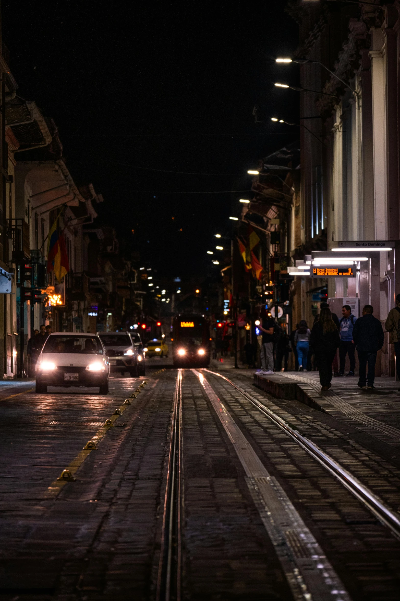 people stand near the tracks as traffic begins to flow past