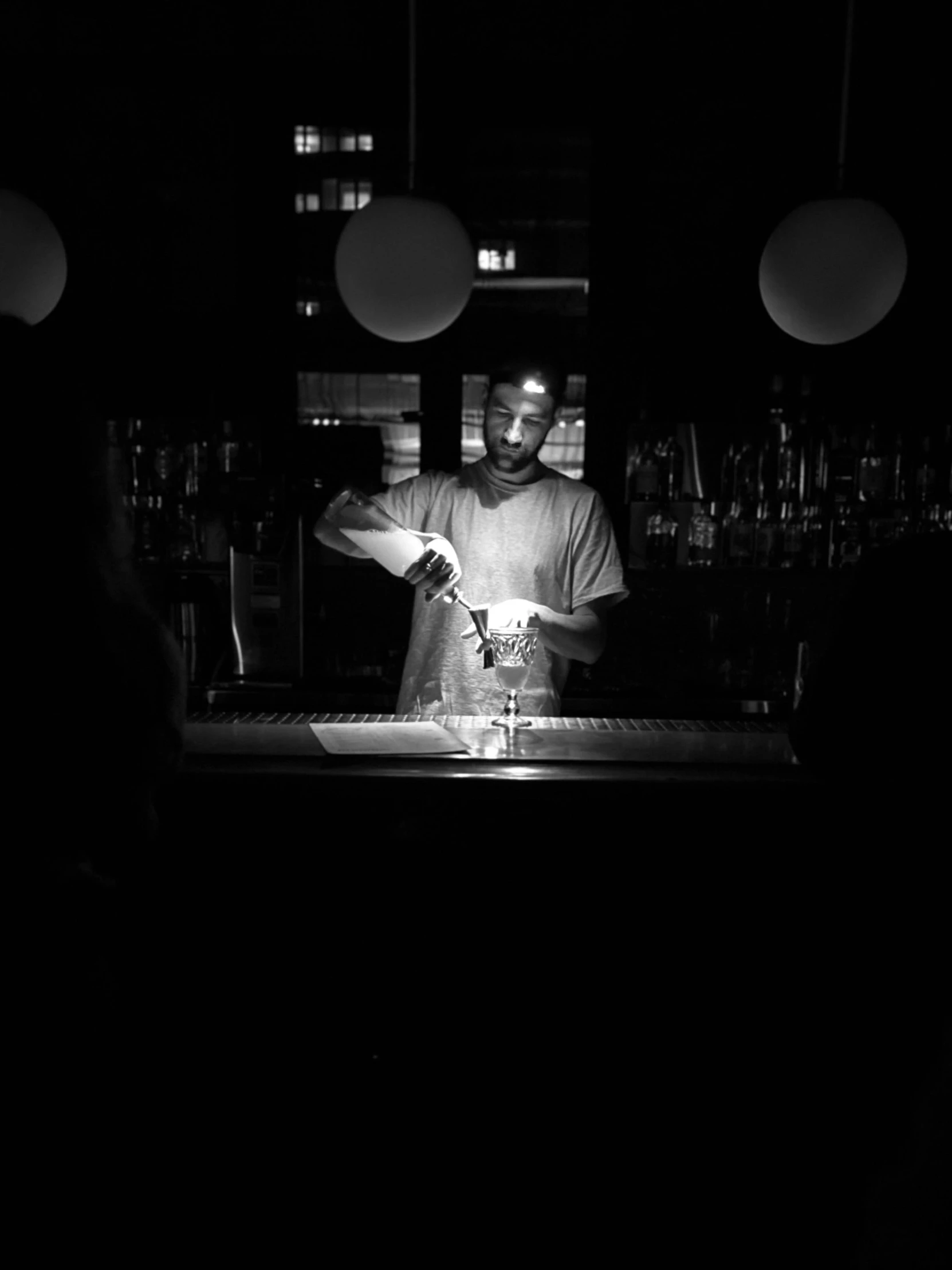 a man standing behind a bar making a drink