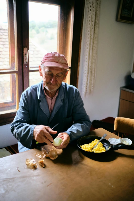 an older man sitting at a kitchen table preparing food