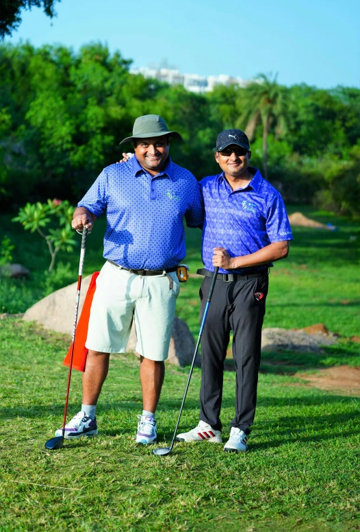 two men are holding golf clubs posing for a picture