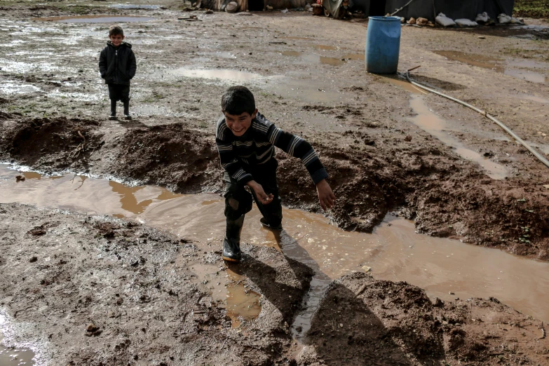 two men are walking through a muddy area