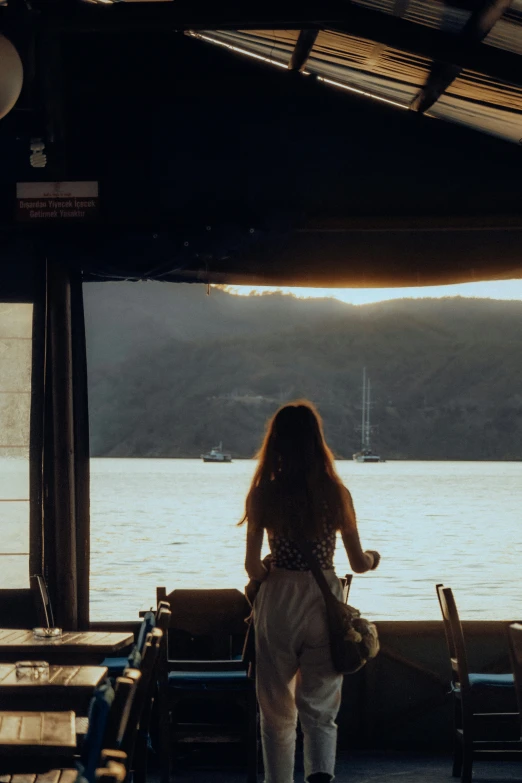 woman carrying her purse across a wooden deck near a body of water