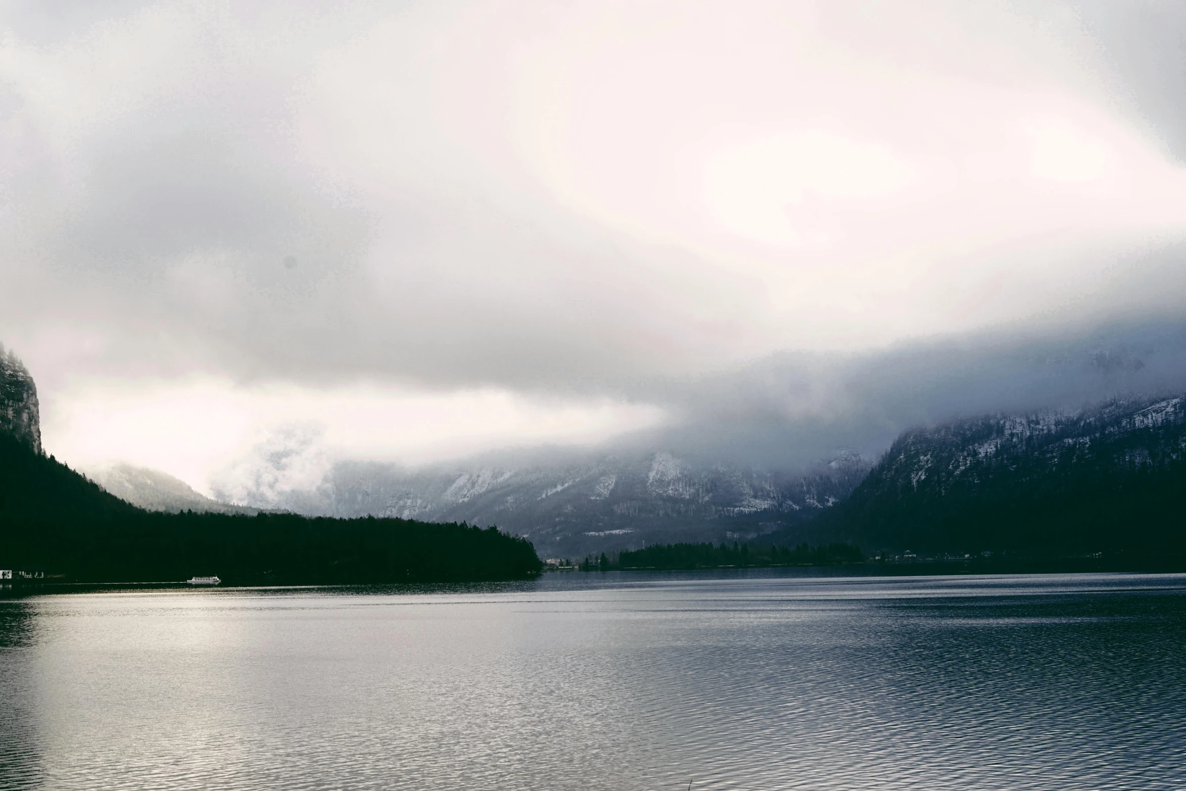 some water mountains and clouds are in the sky