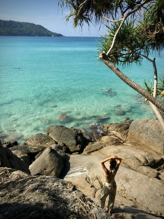 a  standing on a large rock near the ocean