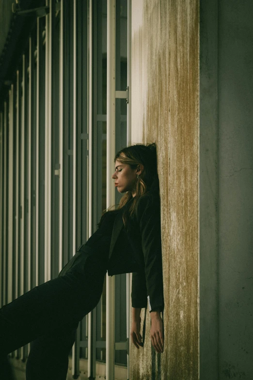 a woman leaning against a wall looking out at the street