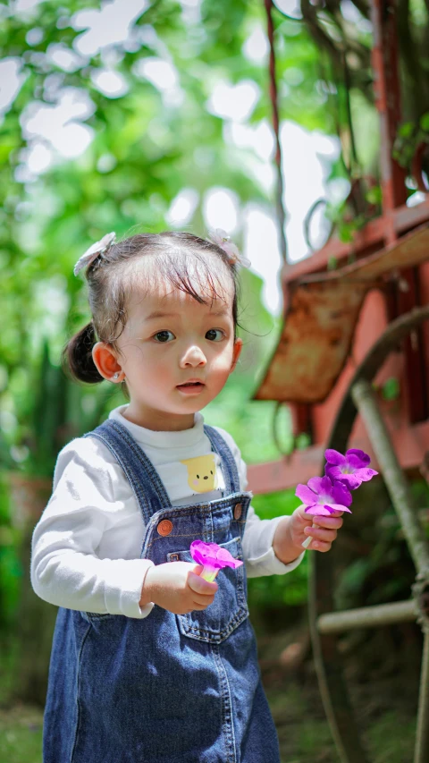 a little girl holding some flowers near her face