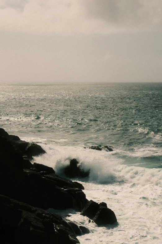 black and white po of ocean, rocks and lighthouse