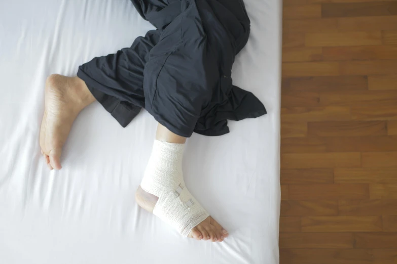 a woman laying on top of a bed with a cast on her leg