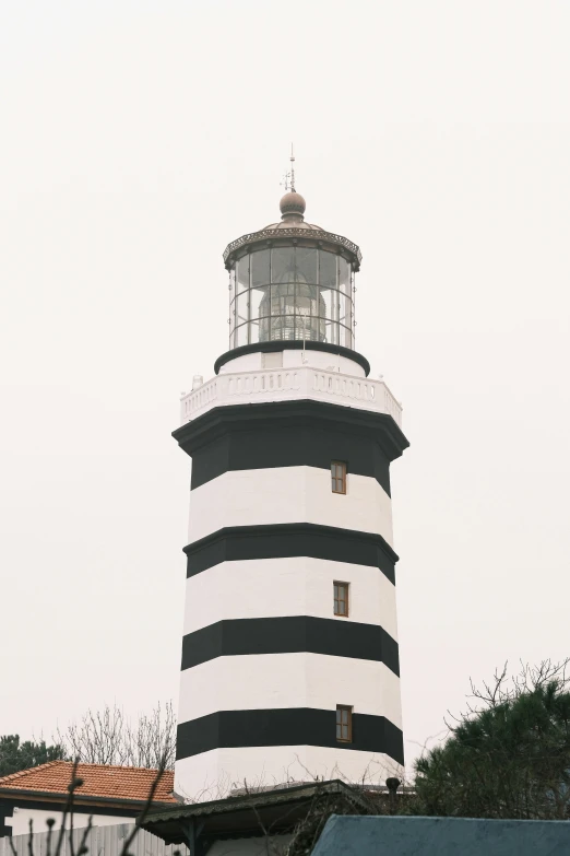a black and white lighthouse on a foggy day