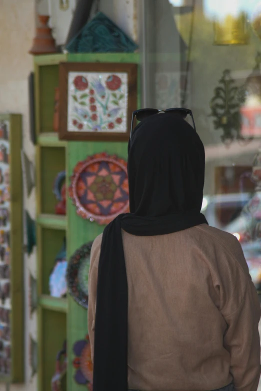 a woman in a hoodie walking past some colorful plates