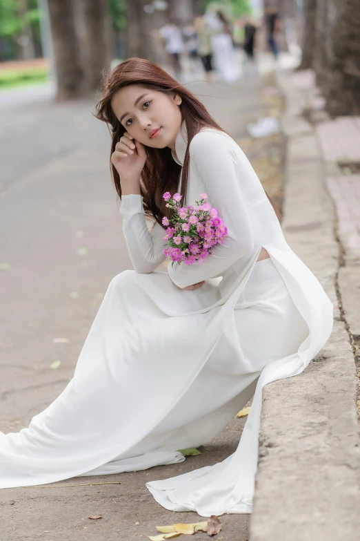 the woman is holding a bouquet of flowers and sitting on the curb