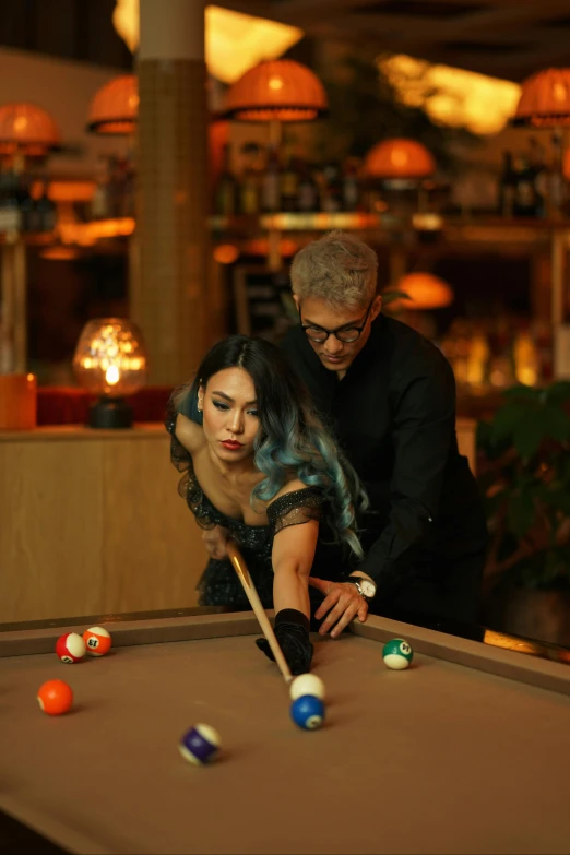 a woman plays pool while a man watches