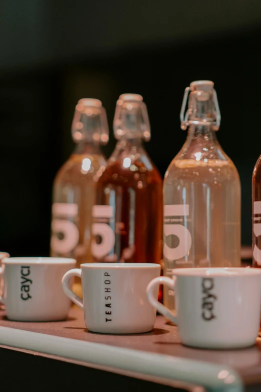 three small cups sit beside two large bottles