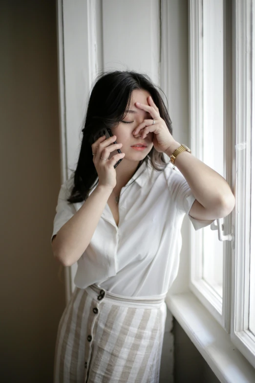 a woman holding her hands to her eye and posing next to the window