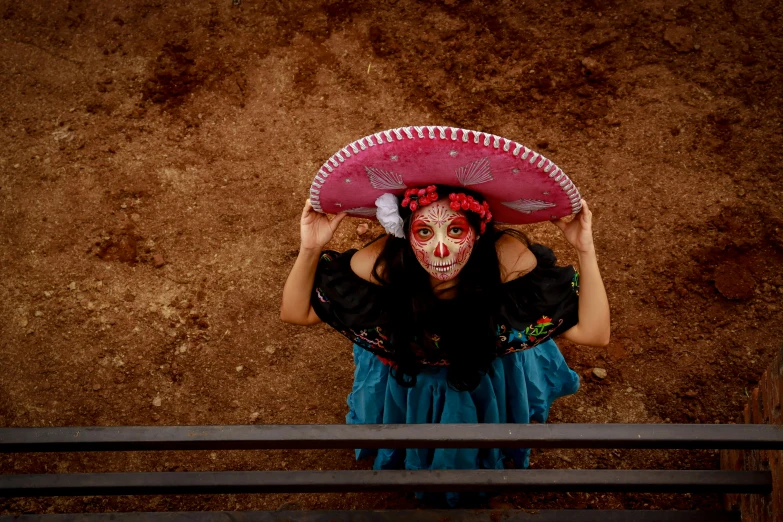 there is a woman with painted face holding up a pink sombrero