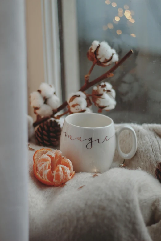 some cotton flowers on a table and a mug