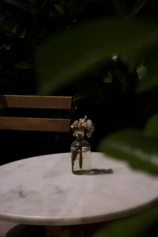 vase with small flowers on marble table in outdoor setting
