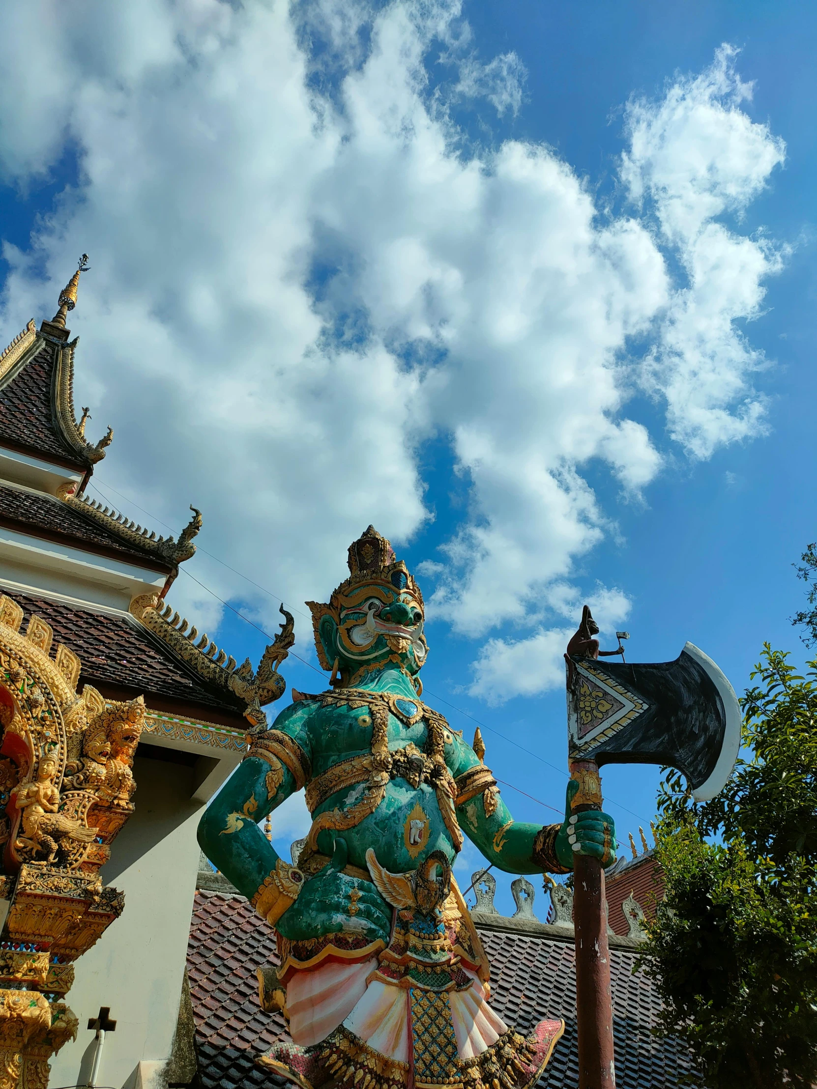 a statue with an axe stands near a blue sky