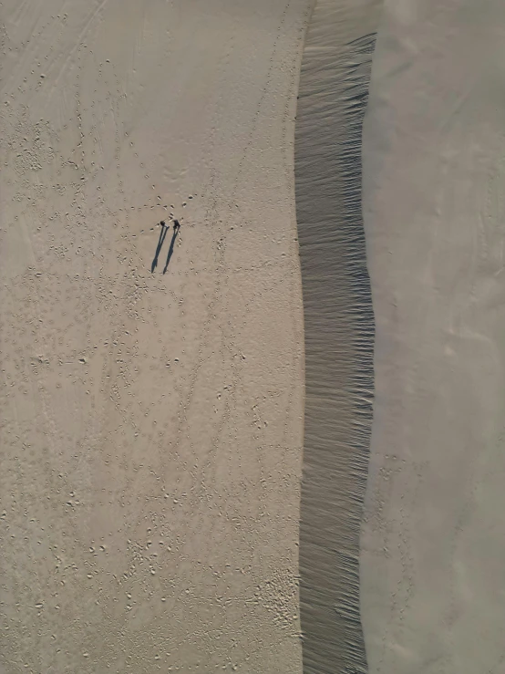 a person standing on the sand at the beach with their surfboard