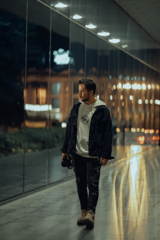 a man walks on the sidewalk while wearing a hoodie