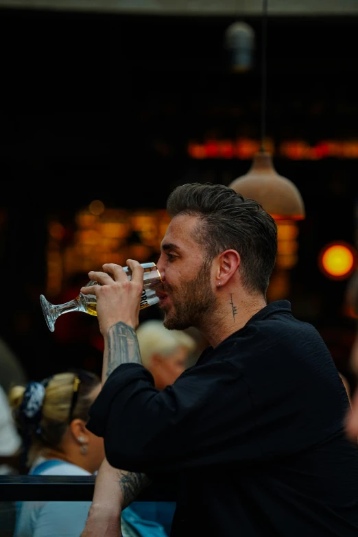 a man drinking wine from a glass at an event