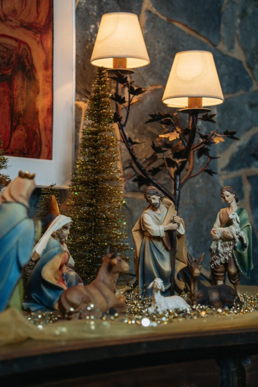 christmas scene featuring three nativity figures next to an old style lit christmas tree