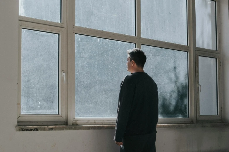 a man standing in front of a window looking outside