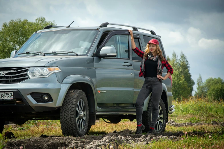 a girl in red is standing beside a grey suv