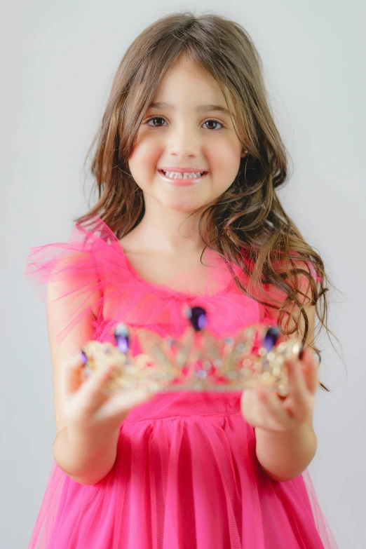 a little girl in a pink dress is holding a crystal object