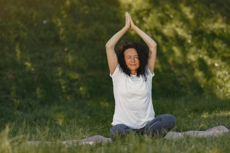 woman in white shirt doing yoga outdoors on a sunny day