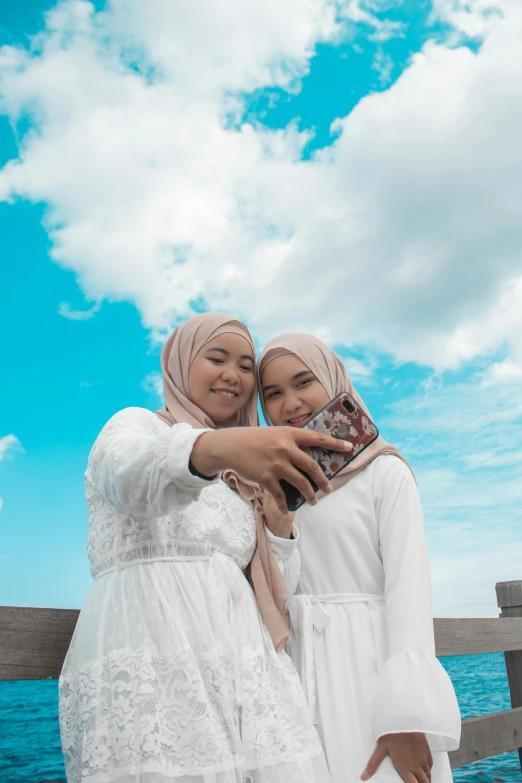 two women dressed in muslim garb holding a book