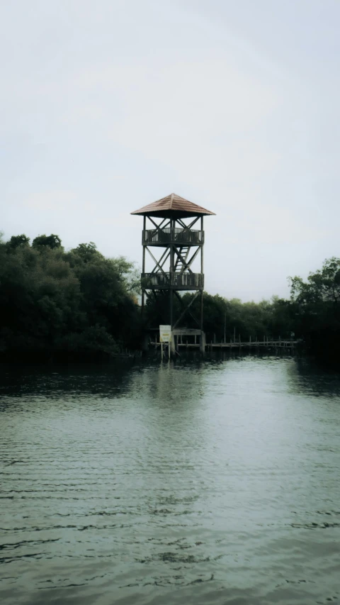 a lifeguard stand stands above water on a cloudy day