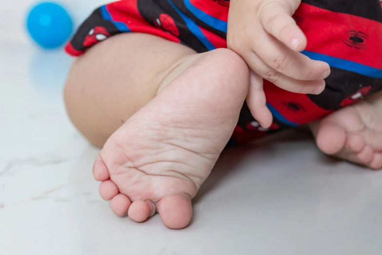 baby feet and leg in red and black striped diaper