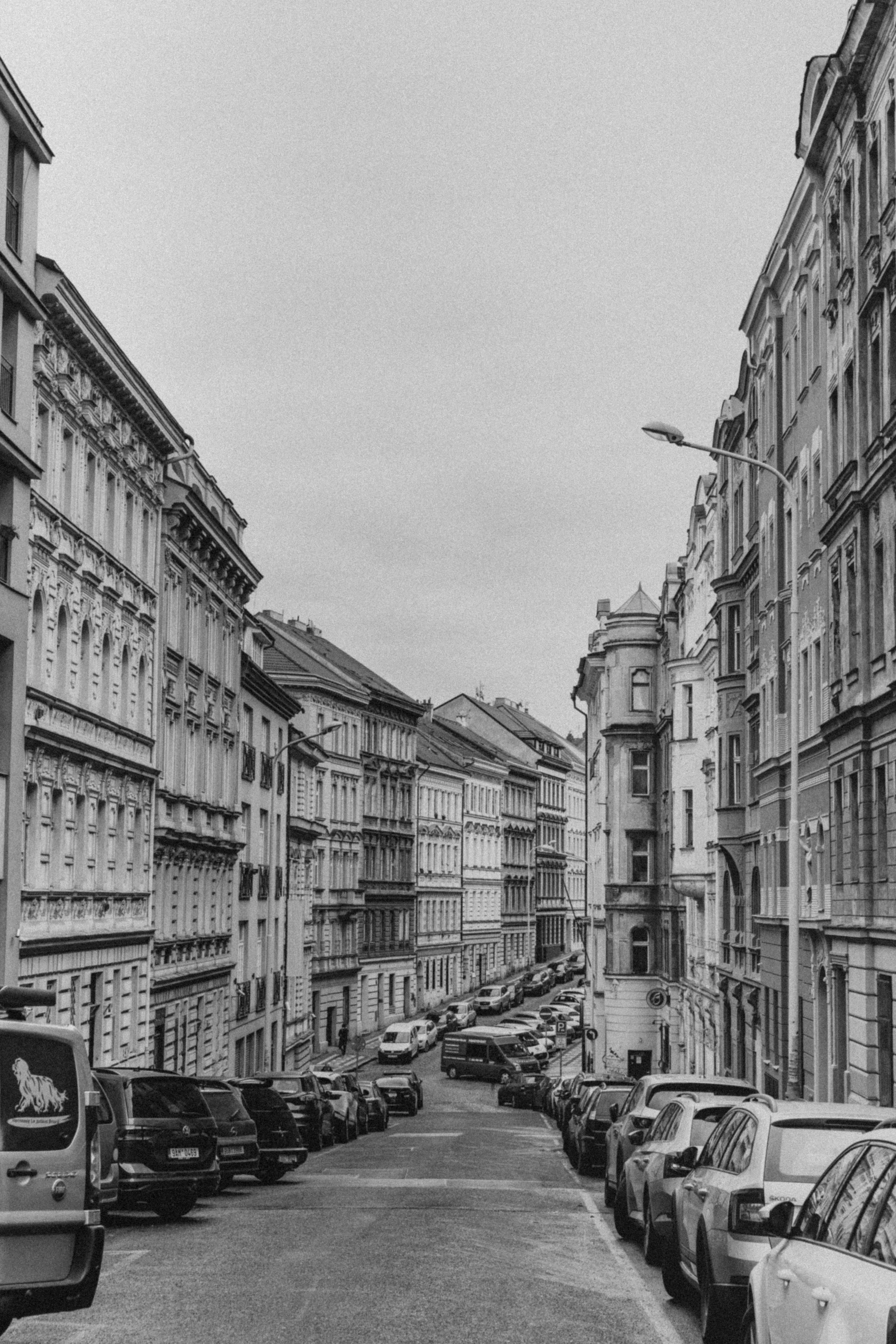 a black and white po of a street with many parked cars