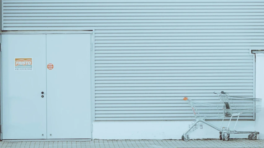 a small shopping cart parked in front of a warehouse door