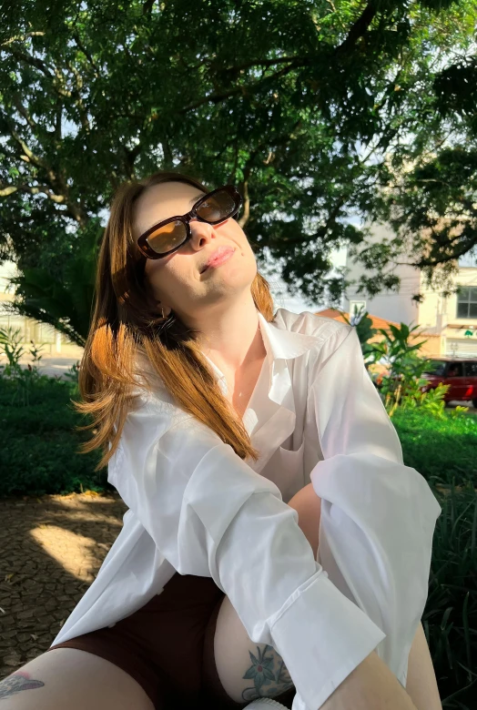 a young lady is sitting in a park on the grass