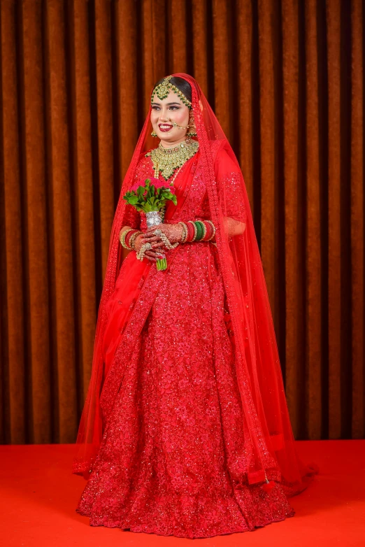 a woman wearing a red dress with gold accessories, a tiara and holding a rose