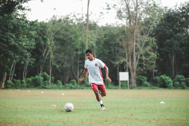 a man in the grass kicking around a soccer ball