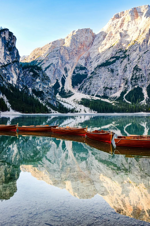 a long boat docked at the base of a mountain lake