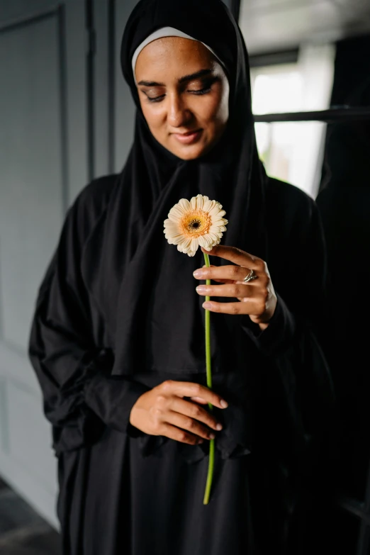 a woman with a headscarf is holding a flower