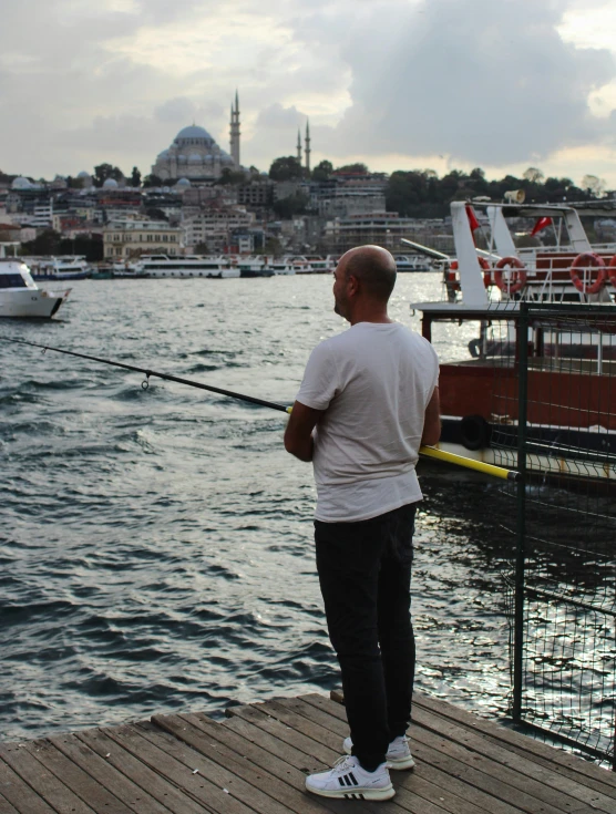 a man holding a fishing pole while standing on a dock