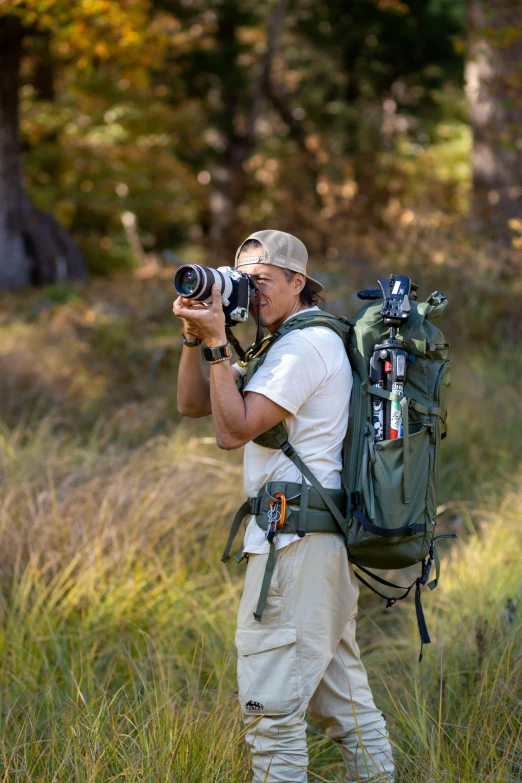 man in a field, holding a camera and taking a po